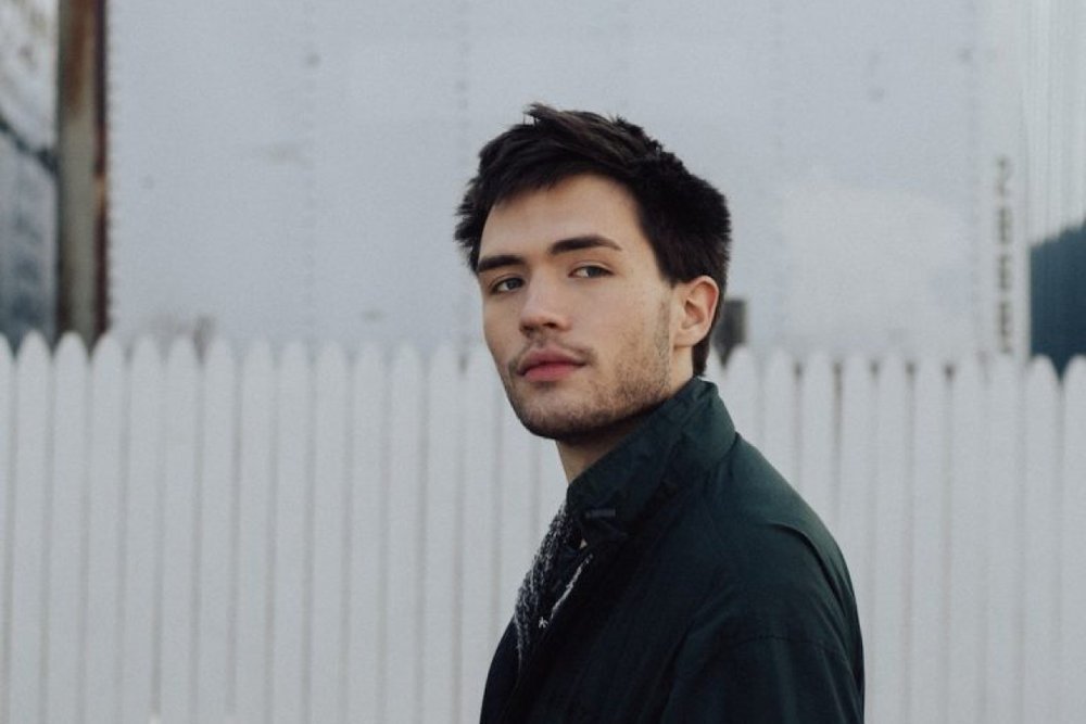 Portrait of a young man in front of a white fence